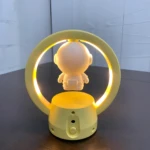 Lámpara de mesa LED amarilla con figura de astronauta flotante dentro de un aro luminoso.