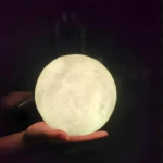 Lámpara LED luna 15cm, 16 colores, posada en mano, ideal para decoración y ambiente relajante.