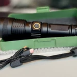 Linterna LED negra potente 2500 lúmenes en estuche verde con cable USB y cordón.