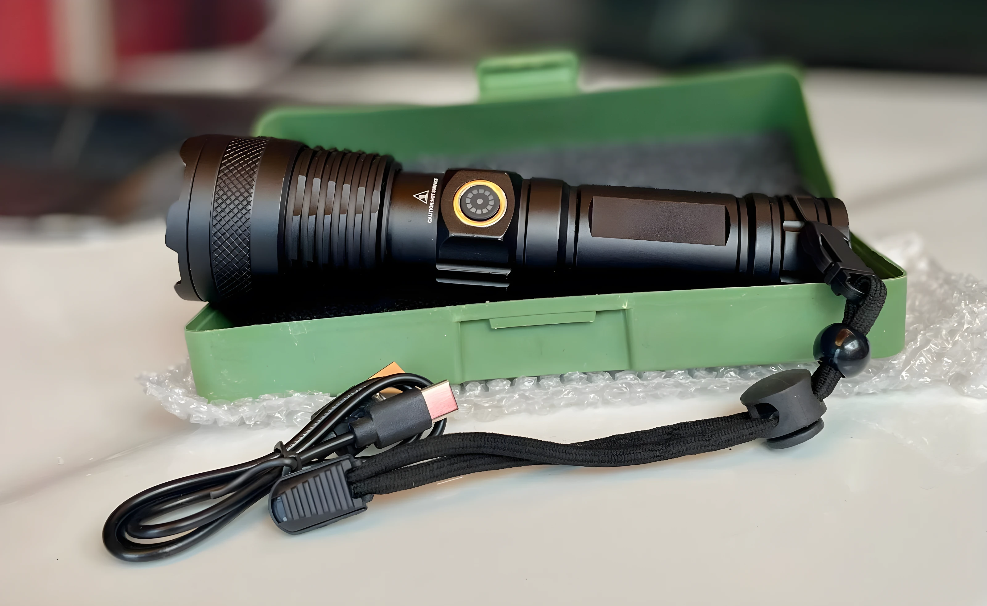 Linterna LED negra potente 2500 lúmenes en estuche verde con cable USB y cordón.