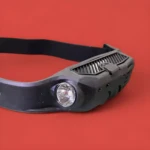 Linterna minera negra con sensor, para cabeza, con banda ajustable, vista frontal detallada.