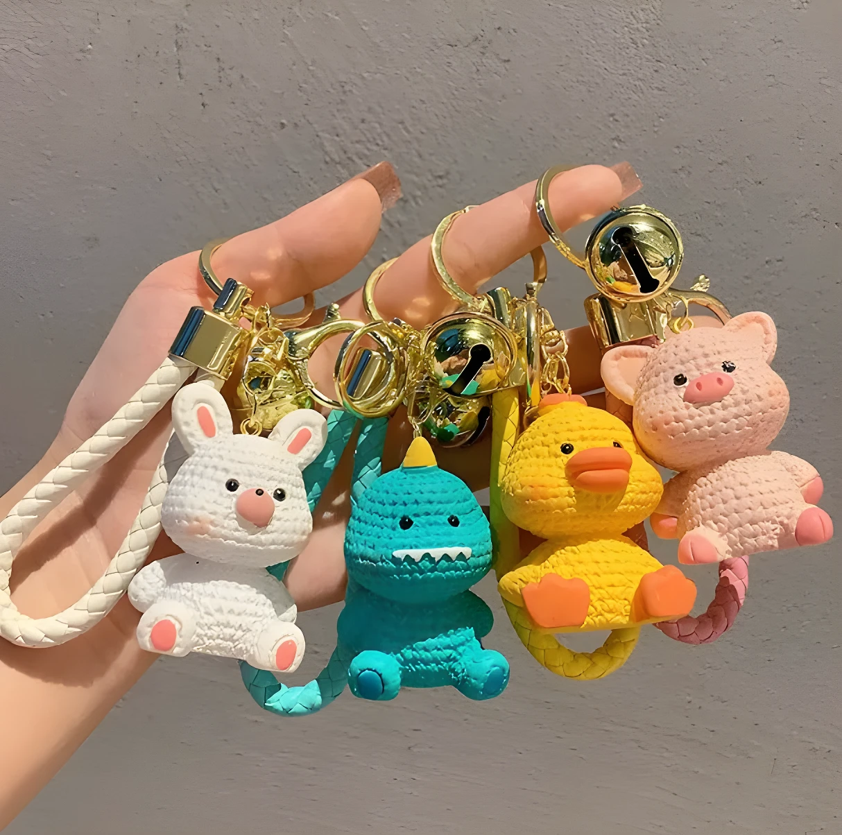 Set x4 llaveros de felpa: conejo blanco, dinosaurio azul, pato amarillo y cerdo rosa, con detalles dorados.