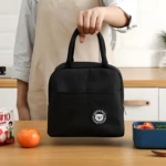 Lonchera térmica negra con estampado de oso, ideal para transportar alimentos.