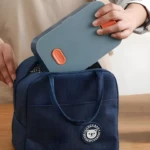 Lonchera térmica azul oscuro para comidas, con compartimento principal y detalle de oso, ideal para transportar alimentos.
