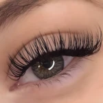 Ojo con pestañas postizas largas y densas, negras, con mirada profunda y cejas definidas.