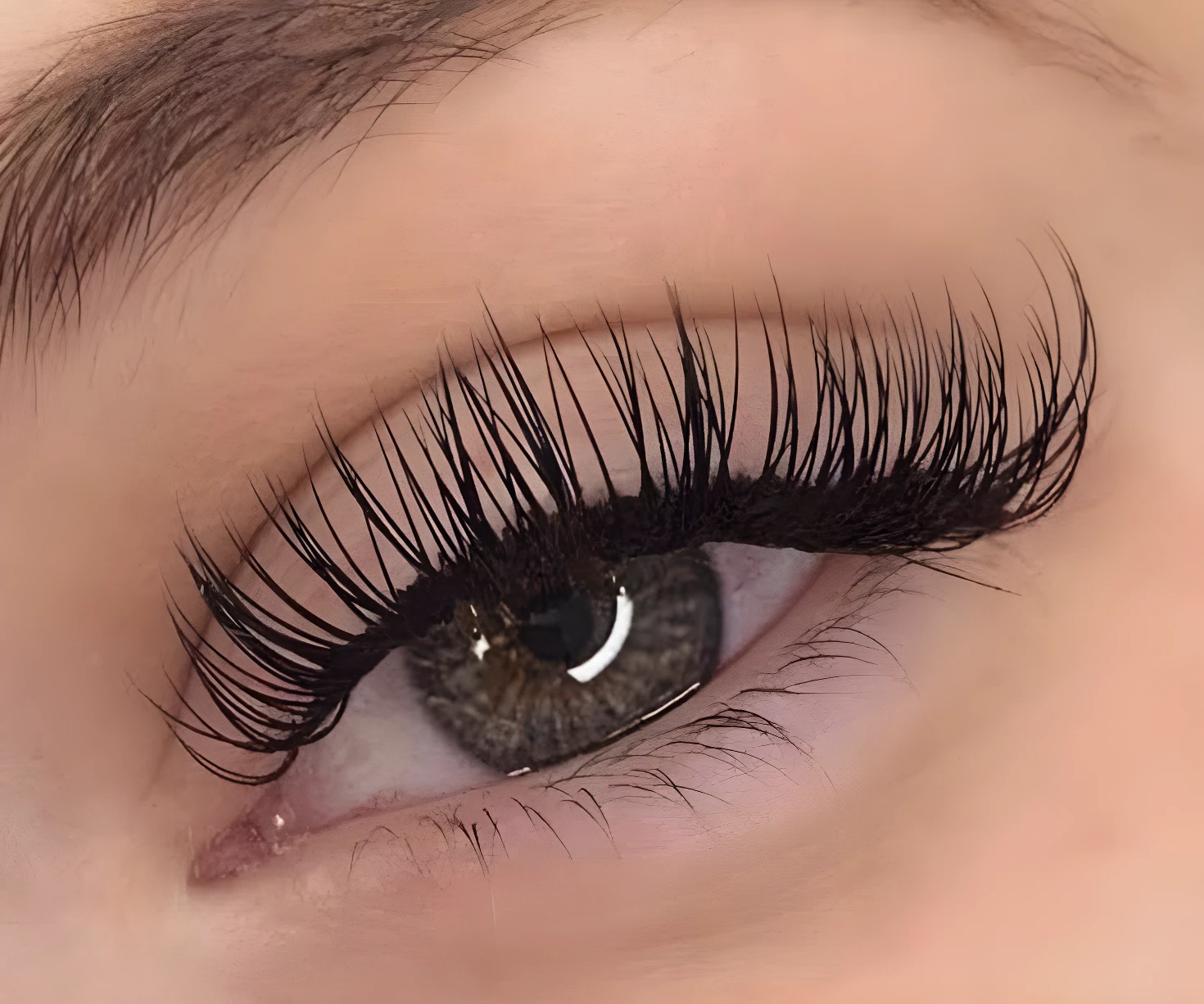 Ojo con pestañas postizas largas y densas, negras, con mirada profunda y cejas definidas.