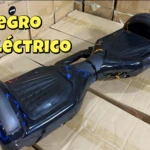 Patineta eléctrica autoequilibrada negra con diseño de rayos azules y naranjas, ideal para niños.