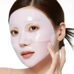 Mujer con mascarilla facial PDRN Salmón Medicube, unificando tono y fortaleciendo barrera cutánea.