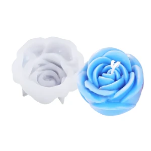 Molde de silicona flexible para repostería junto a una vela azul con forma de rosa detallada, ideal para manualidades y decoración de postres.