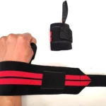 Muñequeras deportivas elásticas negras con franjas rojas, una puesta en mano y otra separada.