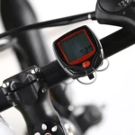 Odómetro para bicicleta con pantalla digital negra y marco rojo, marca 7.20, montado en manillar.