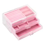 Joyero organizador compacto transparente con cajones rosados y compartimentos para anillos.