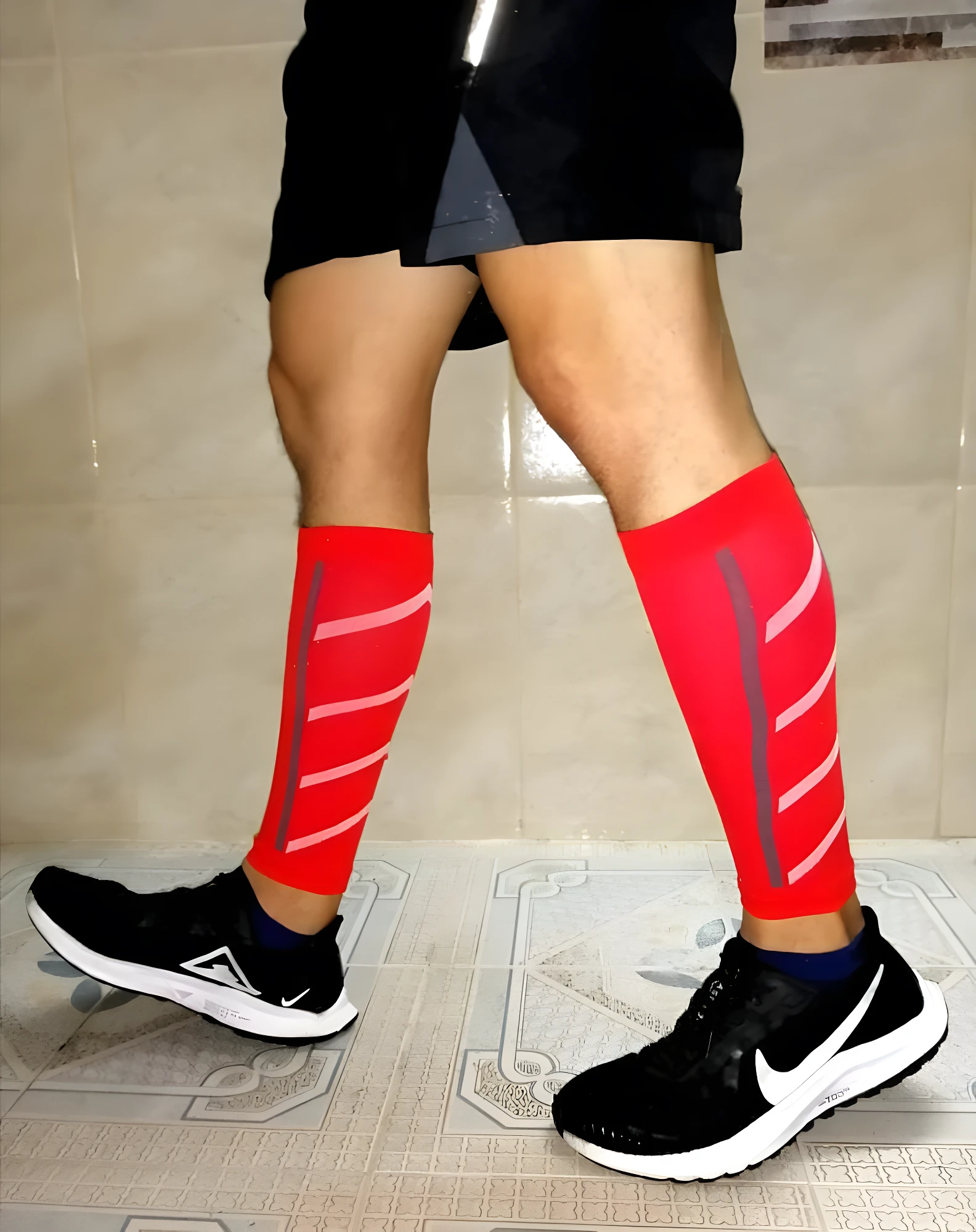 Pantorilleras de compresión running rojas con líneas blancas reflectantes, calzado deportivo negro.