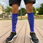 Pantorillera de compresión azul para running con detalles grises, vista frontal inferior con zapatillas negras.
