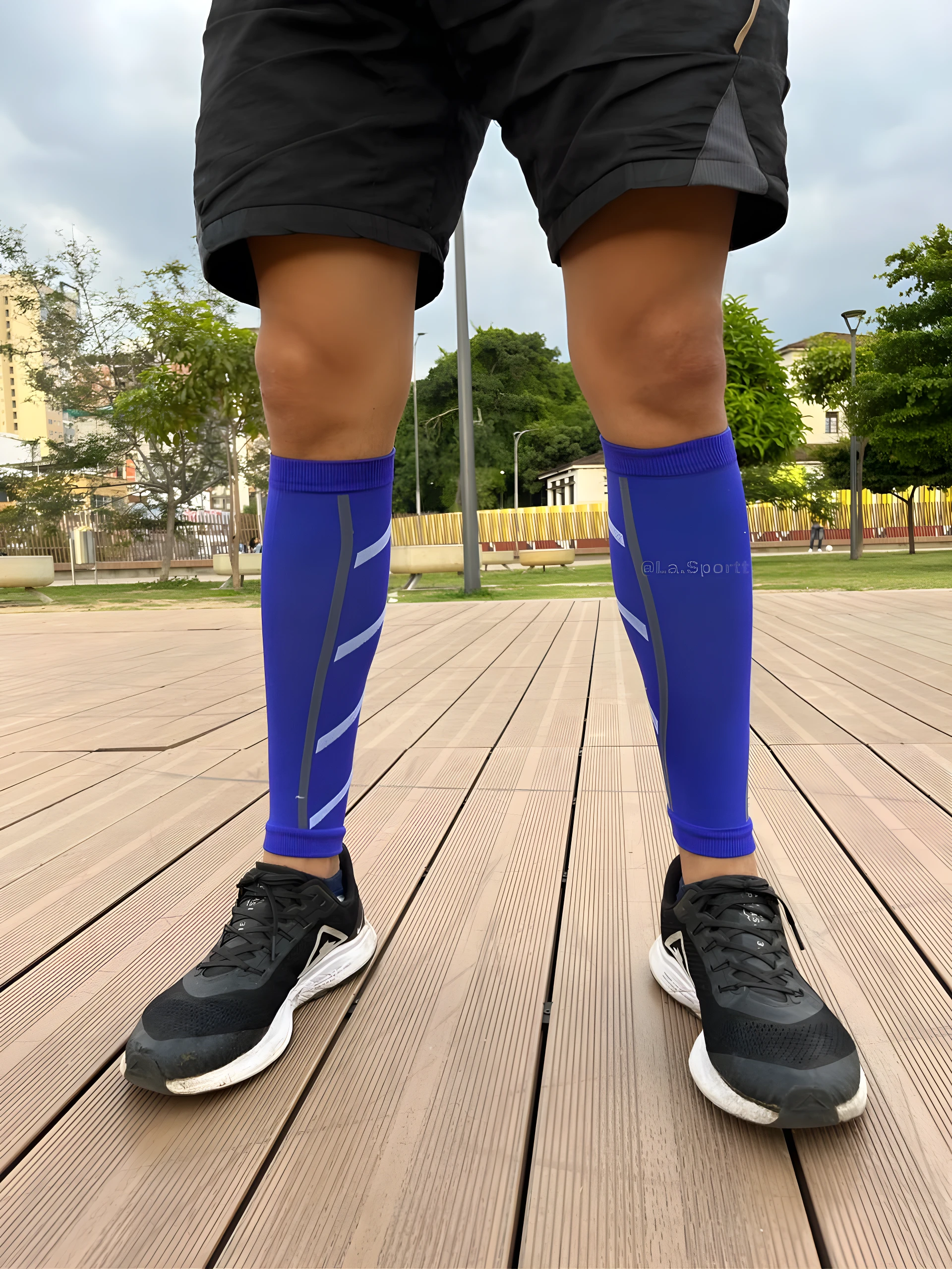 Pantorillera de compresión azul para running con detalles grises, vista frontal inferior con zapatillas negras.