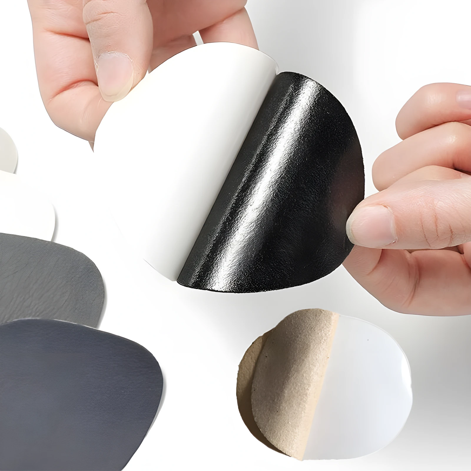 Parches reparadores de zapatos adhesivos negros y grises, mostrando texturas y parte del adhesivo.