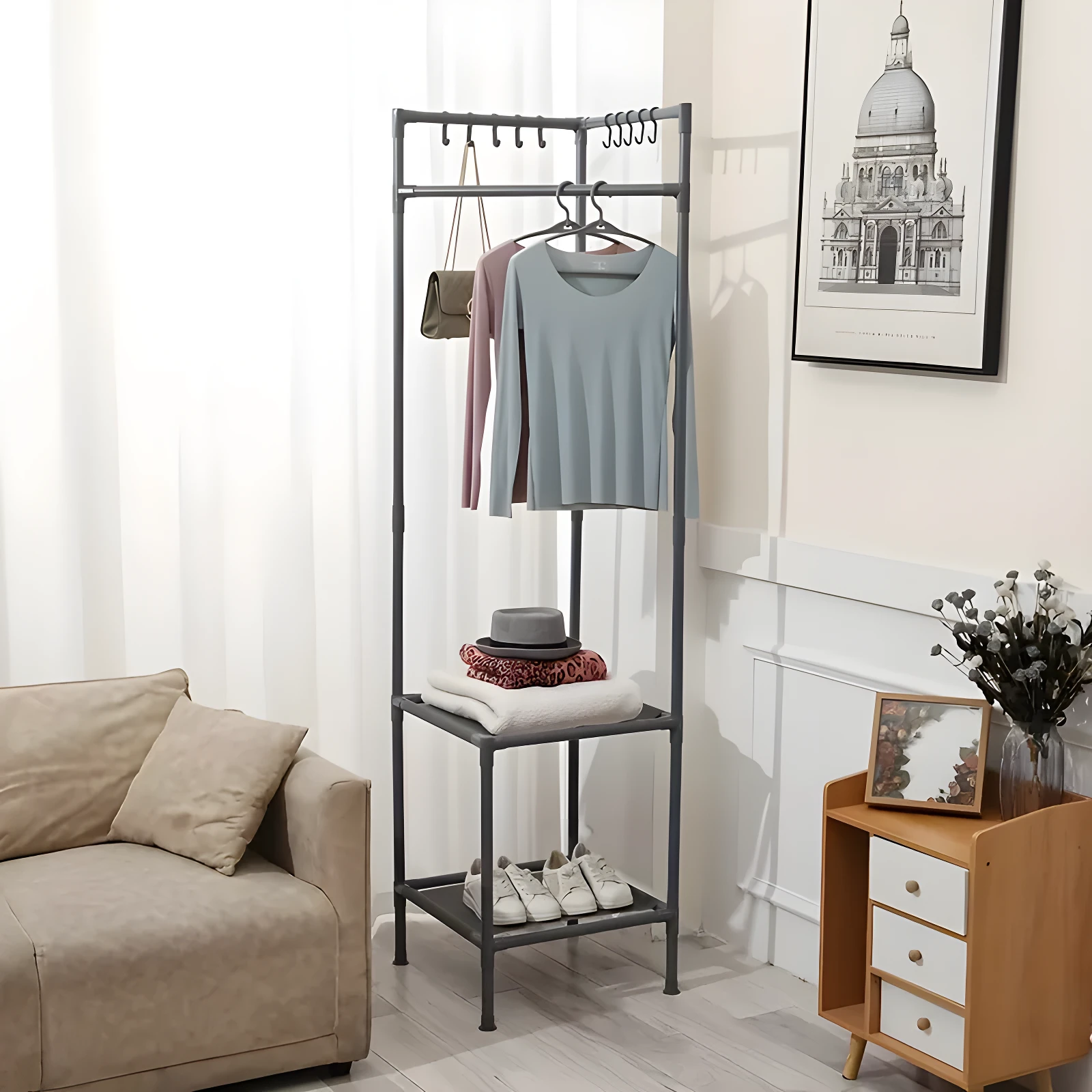 Perchero esquinero triangular gris con dos estantes, cuelga ropa y exhibe accesorios.