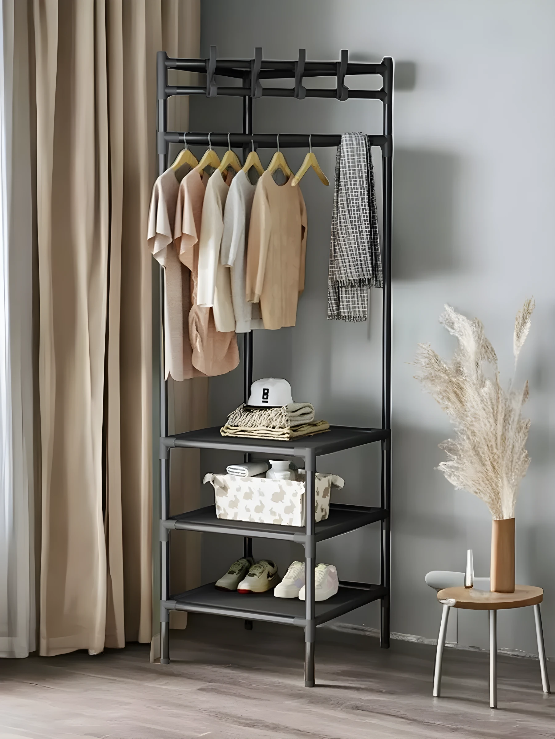 Perchero esquinero triangular negro con estantes, organizado con ropa, gorra y zapatos.