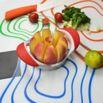 Picador de manzana rojo y blanco con trozos de manzana y tomate, sobre tapete con líneas de colores.