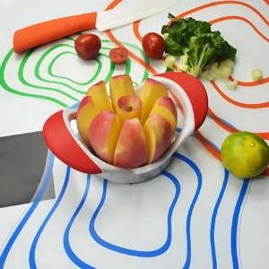 Picador de manzana rojo y blanco con trozos de manzana y tomate, sobre tapete con líneas de colores.