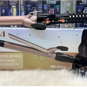 Pinza rizadora Reimiogton Keratin 3D Pro modelo RE-2502, color rosa metalizado con mango negro texturizado, sobre su caja exhibidora en superficie peluda.