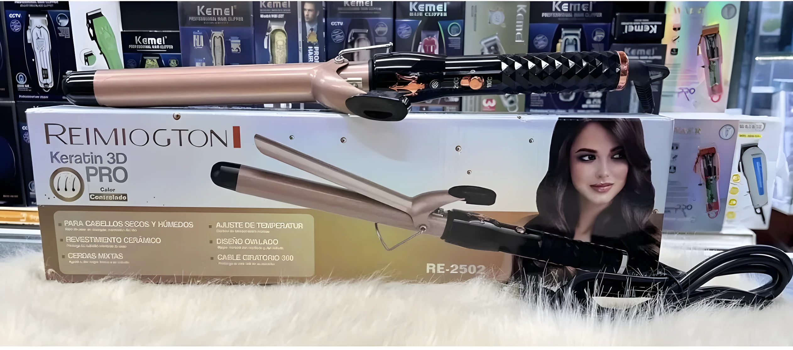 Pinza rizadora Reimiogton Keratin 3D Pro modelo RE-2502, color rosa metalizado con mango negro texturizado, sobre su caja exhibidora en superficie peluda.