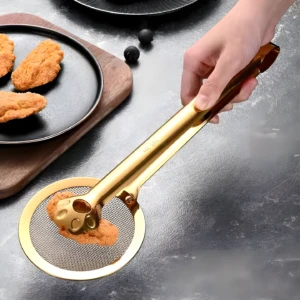 Pinzas doradas de acero inoxidable para servir y escurrir, con tres alitas crujientes en el recogedor de malla.