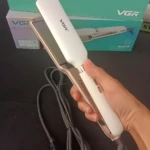 Plancha para cabello VGR blanca y champaña con placas flotantes, sostenida por una mano frente a su caja original que indica una temperatura de 450 grados.