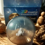 Esfera de cristal con astronauta flotando, base de madera, sobre superficie texturizada.