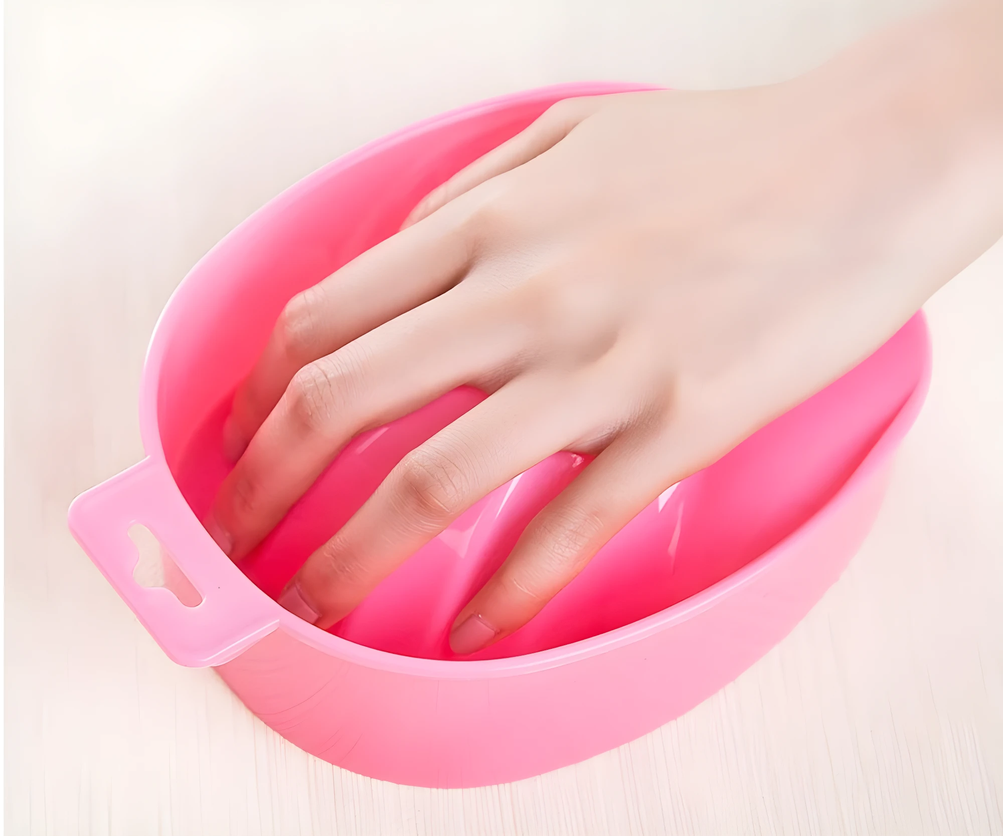 Recipiente rosado para manicure con diseño ergonómico y soporte interior para apoyar los dedos mientras se remojan las uñas en el tratamiento de belleza.