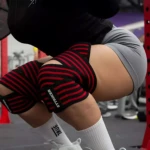Rodilleras de compresión rojas y negras con logo STRIKER, usadas en entrenamiento de fuerza.