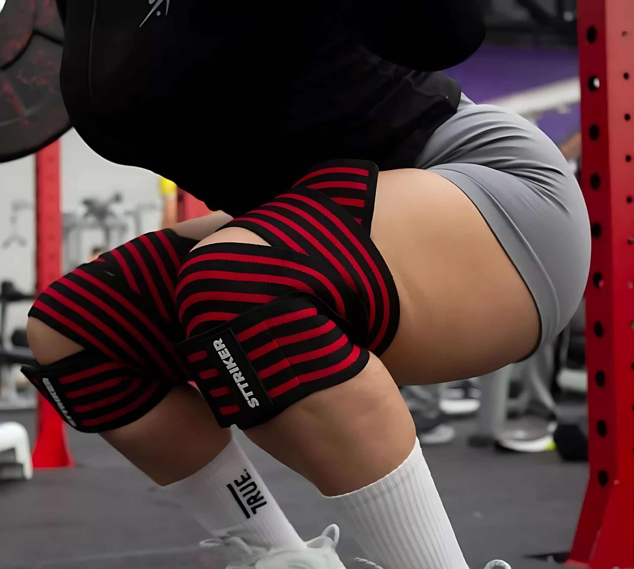 Rodilleras de compresión rojas y negras con logo STRIKER, usadas en entrenamiento de fuerza.