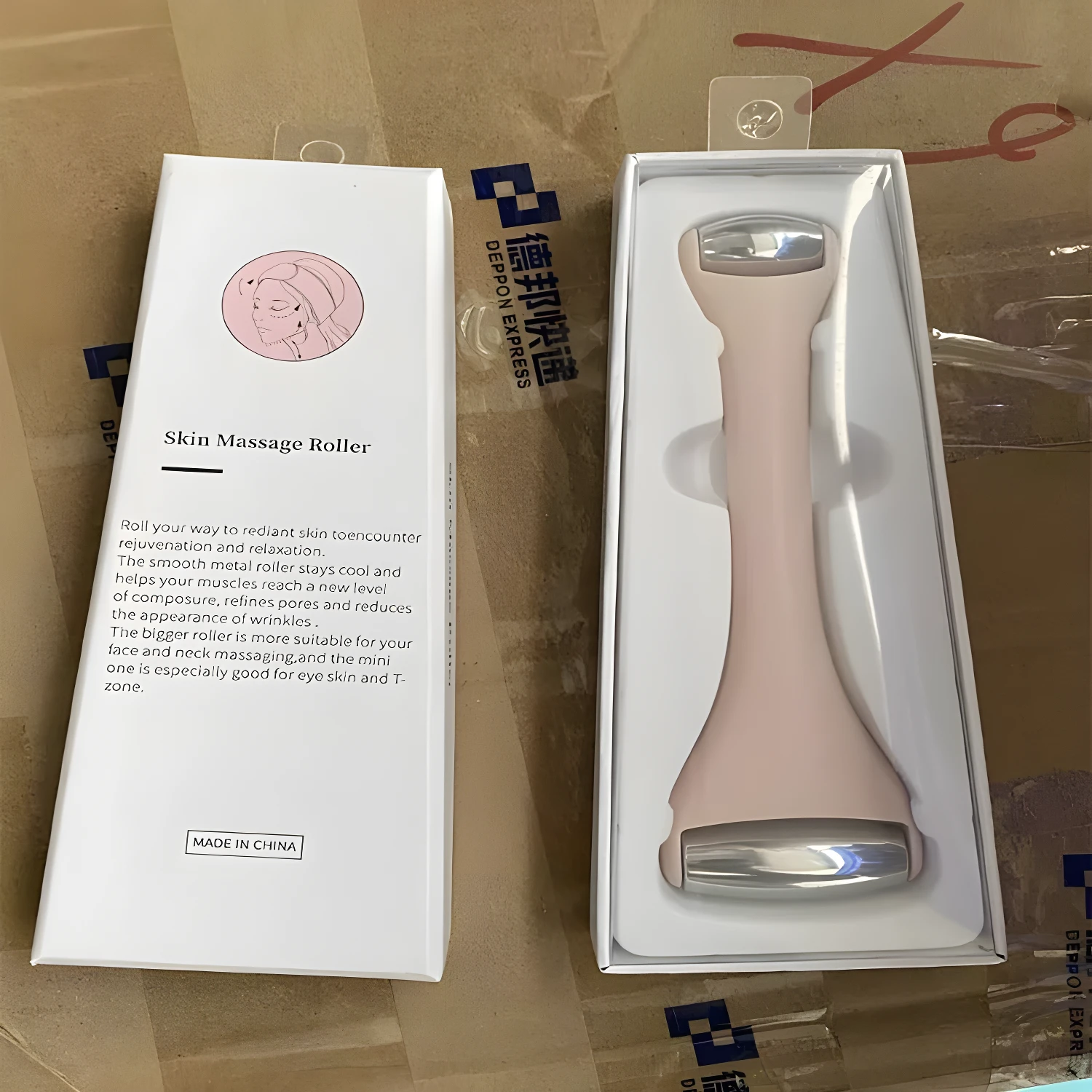 Rodillo facial color rosa metálico doble punta en caja, ideal para desinflamar y refrescar la piel.