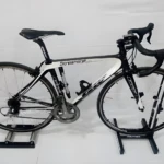 Bicicleta de ruta negra y blanca marca Streamline en rodillo de entrenamiento interior.