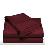 Juego de sábanas dobles color vino c las, diseño de rayas finas, apiladas en superficie blanca.