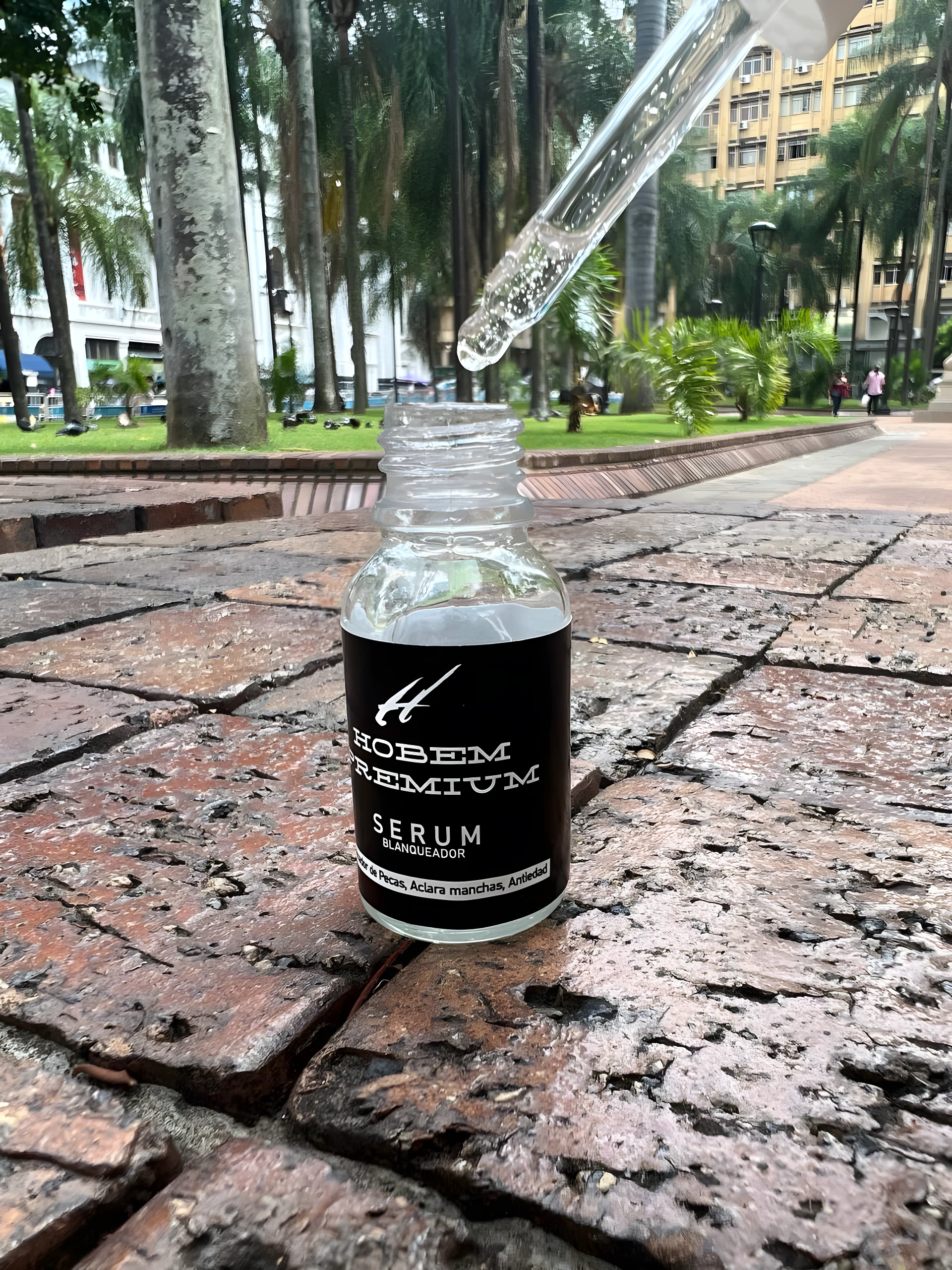 Serum Hobem Premium Aclarante, frasco con gotero sobre ladrillos, ideal para manchas y piel sensible.