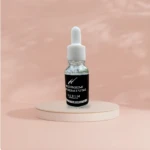 Serum aclarante corporal Hobem Premium en frasco con gotero, sobre pedestal, piel sensible.