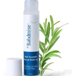 Serum capilar roll-on de 25 ml con aplicador metálico, romero y anagain, junto a una rama de romero fresco.