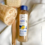 Shampoo Anyeluz 500ml con Gusano de Seda y Biotina, en botella transparente con etiqueta blanca y dorada, al lado de esponjas naturales.