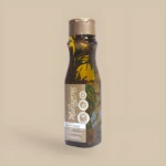 Shampoo Milagro Herbal en botella ámbar con hierbas incrustadas, tapa dorada. Controla grasa y caída.