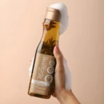 Shampoo Milagro Herbal en botella con hierbas flotando, en mano con espuma.