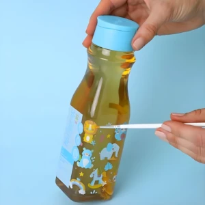 Botella de shampoo natural Milagros con tapa azul, líquido ámbar y etiquetas infantiles de animales.