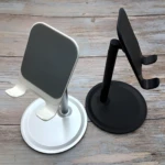 Set x2 soportes de celular en aluminio, uno blanco con base redonda y otro negro con base redonda.