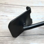 Soporte para celular en aluminio negro, vista lateral de un extremo con brazo extensible.