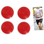 Cuatro sujetadores magnéticos rojos para fijar dorsales de corredor sobre camisetas deportivas.