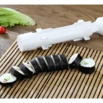 Molde blanco para sushi listo para usar, con rollos de sushi cortados sobre esterilla de bambú.