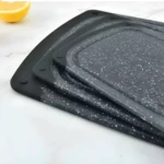 Tabla picadora para cocina con diseño moteado y base negra antideslizante, con un limón al fondo.