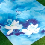 Tapete de yoga profesional azul con diseño de flores de loto blancas, sobre césped verde.