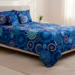 Tendido abullonado azul con diseño floral abstracto para cama doble 1.40, acompañado de almohadas a juego.