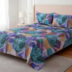 Tendido de cama doble faz con diseño abstracto multicolor en tonos azules, morados y naranjas, estilo moderno, con cojines a juego.